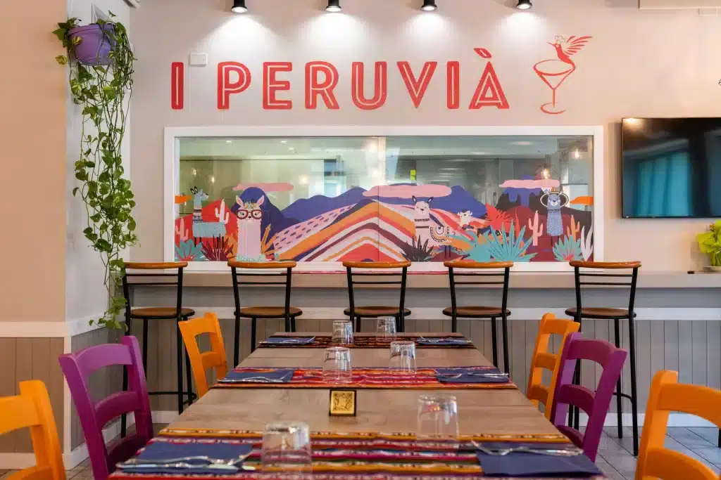 interno del locale i peruvi&agrave; con sedie colorate e murales di alpaca sulle pareti