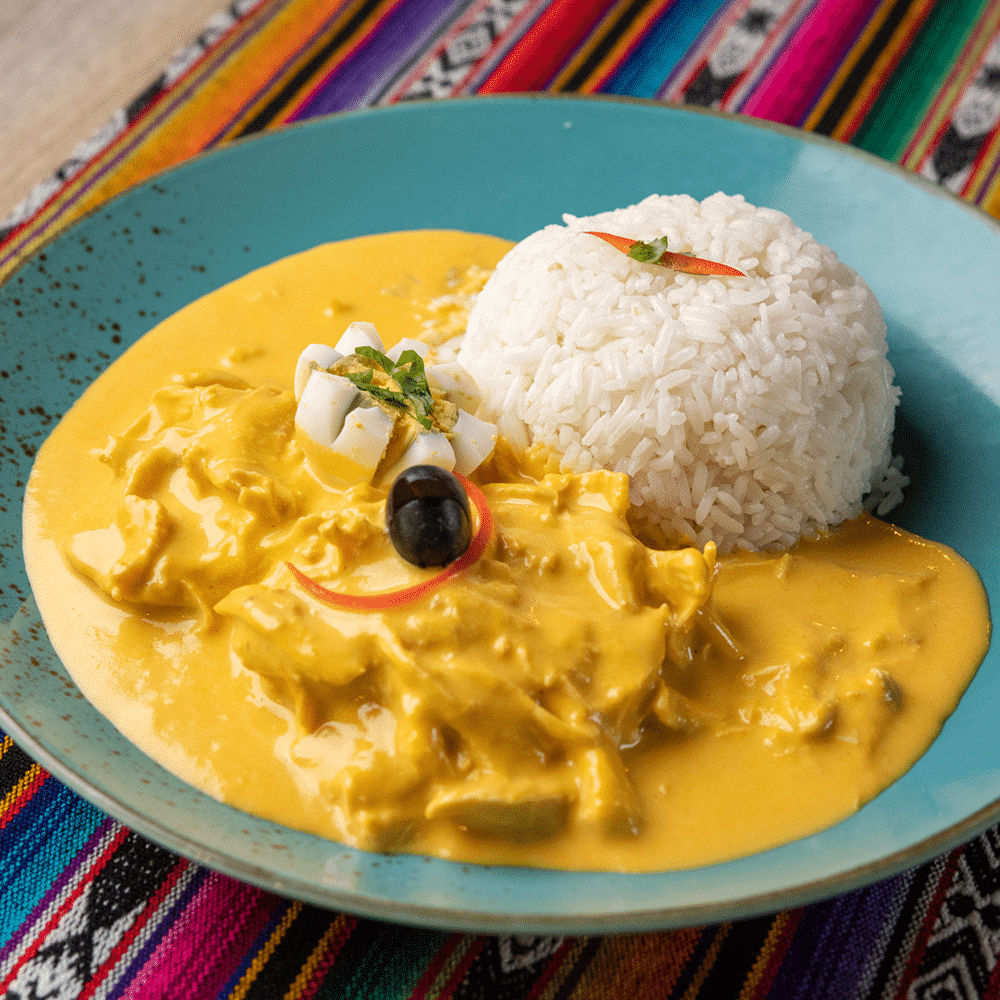 piatto tipico per&ugrave; con pollo in crema di peperoni aji e riso su piatto celeste